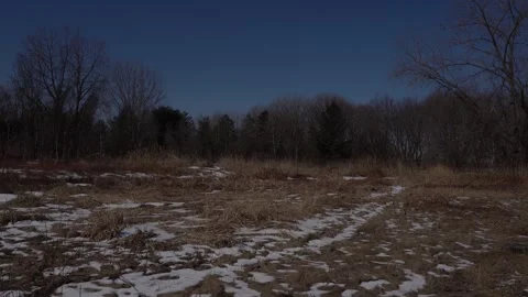 Landscape view of a winter field with patches of melting snow dry brown grass 動画素材 334591716