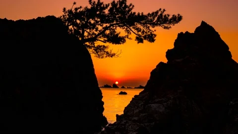 A landscape where the red sun rises among the rocks. Zoom in Vidéo 145740023