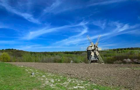 Landscape with a windmill in a plowed field. Stock Photos