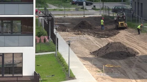 Landscapers workers prepare soil along new flat houses. 4K Stock Footage 56959262