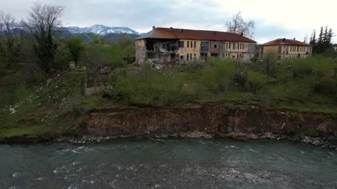 Landslide-damaged house by the river Stock Footage 235984447