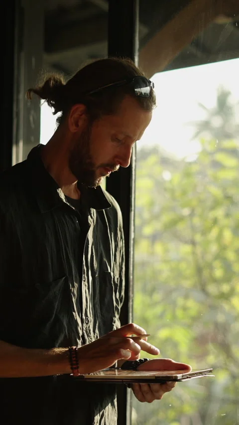 A lanky bearded man looking at the window with his tablet in his hand Video stock 265474715