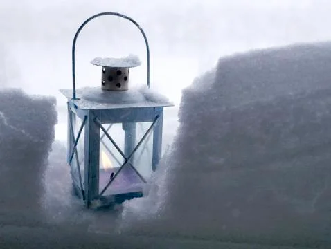 A lantern with a burning candle in the snow Stock Photos