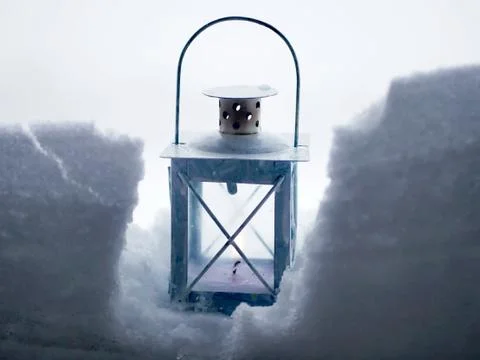 A lantern with a burning candle in the snow Stock Photos