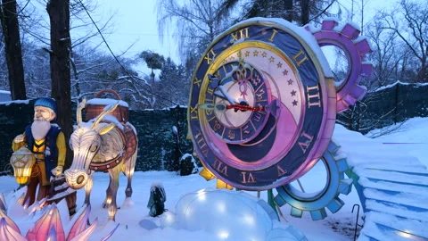 Lantern figures of an old man and a donkey glow brightly in the snowy park.  库存影片 325867393