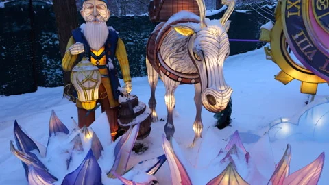 Lantern figures of an old man and a donkey glow brightly in the snowy park.  Stock Footage 325868039