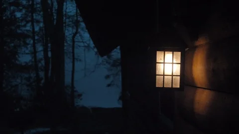 Lantern Glowing at Cabin by Lake at Night Stock Footage