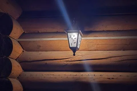 Lantern on a log wall. Stock Photos