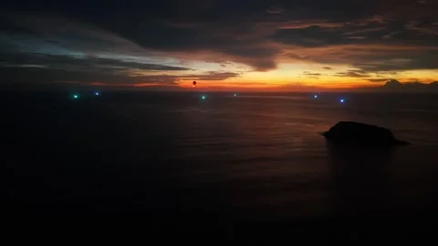 Lantern rises over ocean at sunset, illuminating distant boats and island Vídeos de archivo 342313127