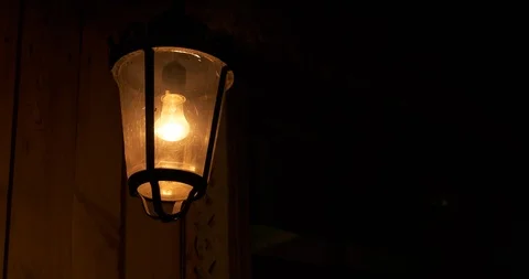Lantern sways in wind, light fall on wooden wall of house, oppressive atmosphere Stock Footage 117987789