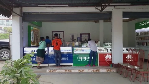Lao costumers stand at counter in celular phone shop, sales people, Sam Neua Vídeos de archivo 76924112