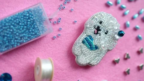Lap Dog brooch on a pink background fabric with beads, threads and pearls Stock Footage 248529008