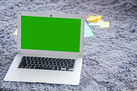 Lap top computer with green screen on gray carpet Stock-Fotos