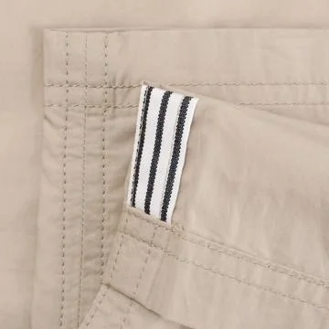 Lapel of thin light beige canvas trousers with striped black and white detail Stock Photos
