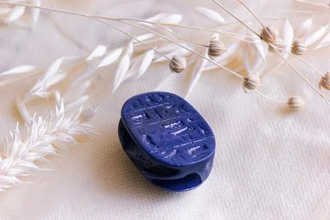 Lapis lazuli scarab amulet base with hieroglyphs on white linen. Stock Photos