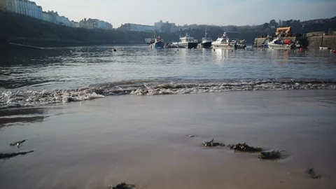 Lapping water on a beach and boats tilt up from sand Stock Footage 116506830