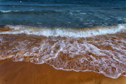 The lapping of the waves on the sandy beach.Small sea waves with crystal clea Stock Photos