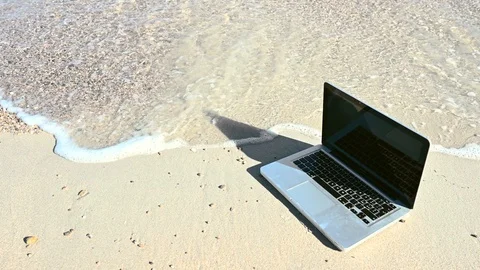 Laptop abandoned on the shoreline risks being washed by the waves of the sea Stock Footage 104652360