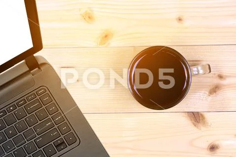Laptop and coffee cup on wood table with burst light. View from above Stock Photos