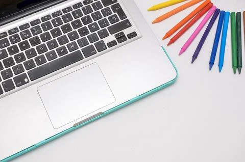 Laptop and crayons on white table promoting creativity and technology Stock Photos