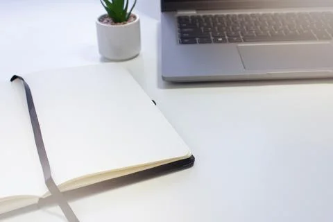 Laptop and notebook on a white table. Stock Photos