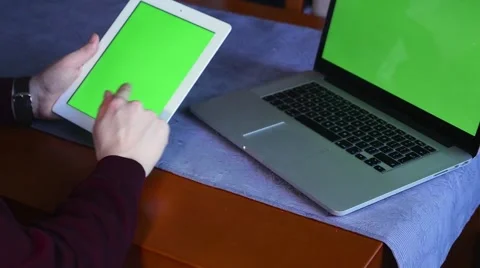 Laptop and tablet pc lying on the table. Man is using tablet pc. Green screen Video stock 61281000