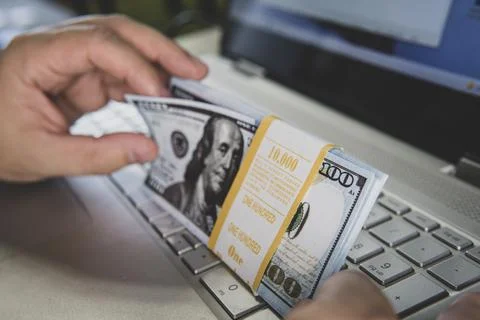 Laptop and US dollar ,Computer notebook and dollar banknotes on a wooden back Stock Photos