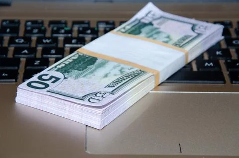 Laptop and US dollar ,Computer notebook and dollar banknotes on a wooden back Stock Photos