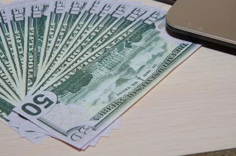 Laptop and US dollar ,Computer notebook and dollar banknotes on a wooden back Stock Photos