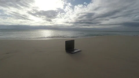 Laptop on a beach as waves crash Stock Footage 73614980