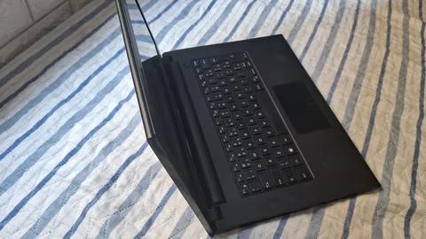 Laptop on a bed. Modern computer device placed on striped bedding for remote Stock Photos