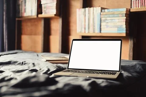 Laptop on the bed with soft light from window. White screen for your advertise Stock Photos
