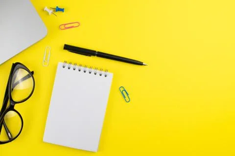 Laptop, black pen, planner notepad, black eye glasses and colorful clips on y Stock Photos