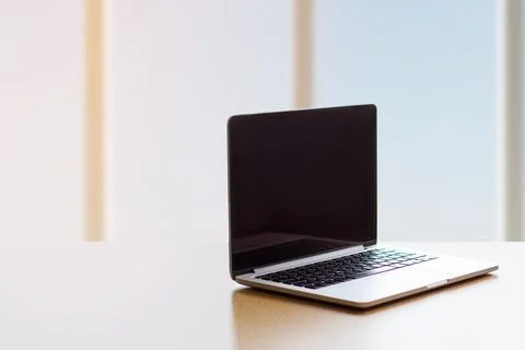 Laptop with black screen on an empty table by the window, copy space Stock Photos