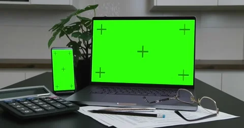Laptop with blank green screen and smartphone on desktop. Stock Footage 237474542