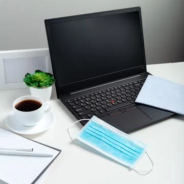 Laptop blank mock up. Protective face medical blue mask, Disinfectant spray.  Stock Photos