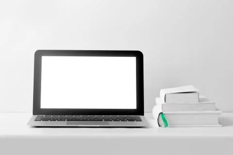 Laptop with blank screen and stack of book on white desk Stock Photos