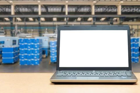 Laptop with blank screen on table with blur warehouse cargo in factory. Smart Stockfoto's