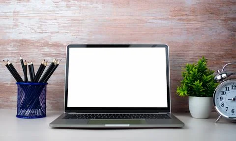 Laptop with blank screen on white table and office supplies on wooden backg.. Foto stock