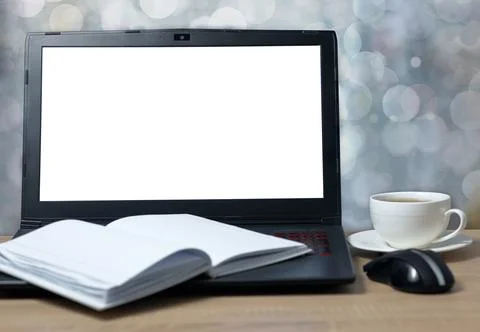 Laptop with blank white screen, a wireless mouse, a notebook and a tea cup Stock Photos
