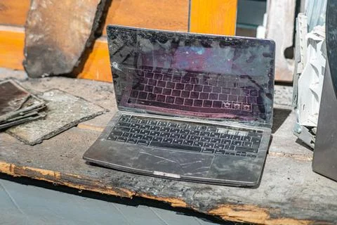 Laptop with a broken screen in cracks on a gray background close up front vie Stock Photos