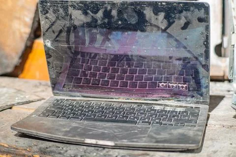 Laptop with a broken screen in cracks on a gray background close up front vie Stock Photos