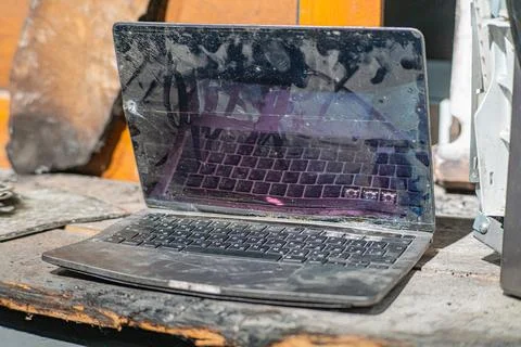 Laptop with a broken screen in cracks on a gray background close up front vie Stock Photos
