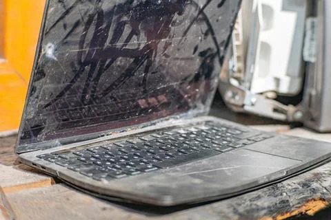 Laptop with a broken screen in cracks on a gray background close up front vie Stock Photos