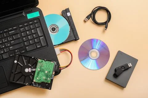 Laptop with CD disk and different memory storage devices on beige background Stock Photos