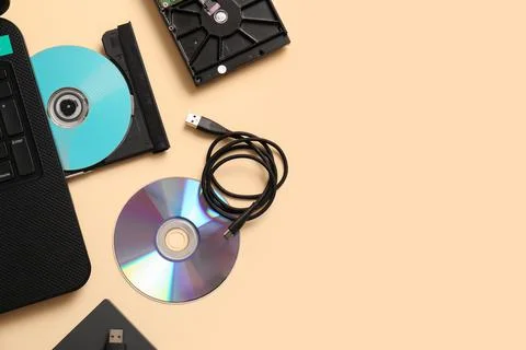 Laptop with CD disk and different memory storage devices on beige background Stock Photos
