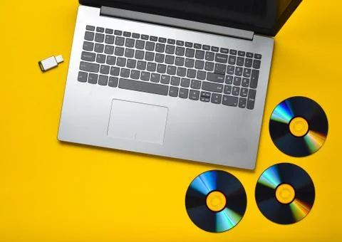 Laptop, CD drives, USB flash drive on a yellow background. Modern and outdate Foto stock