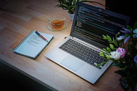 Laptop with code on the screen and notepad with handwritten code on a wood... Stock-Fotos