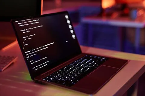 Laptop with coded data on screen standing on desk Stock Photos
