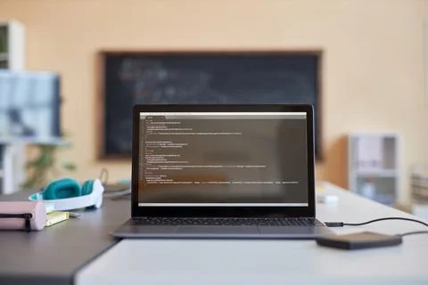 Laptop with coded data on screen standing on desk with headphones Stock Photos